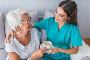 Young,Caregiver,In,Uniform,Hugging,Smiling,Elderly,Woman,During,A